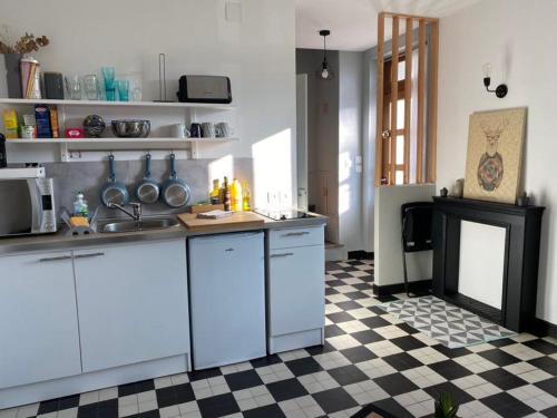 a kitchen with white cabinets and a checkered floor at Joli duplex rénové in Nevers