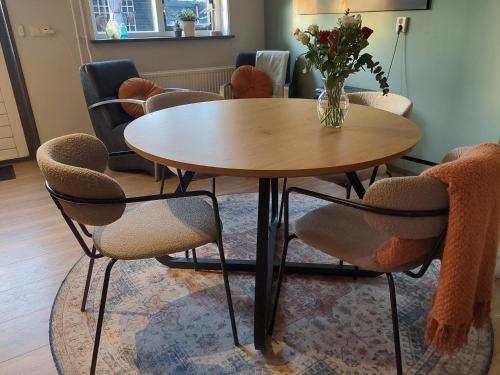 a table with chairs and a vase of flowers on it at Tusken Wad en Wâld in Kollumerzwaag