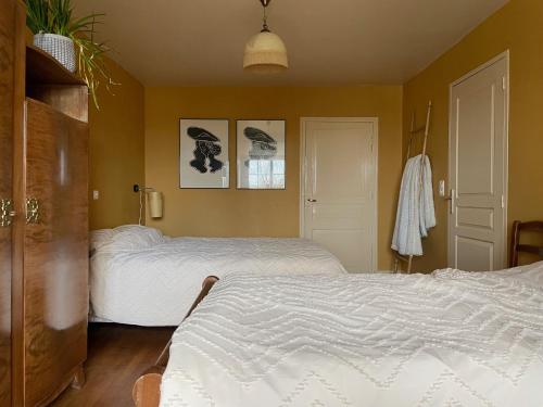 two beds in a bedroom with yellow walls at Veï Lou Quéri in Moutier-Malcard