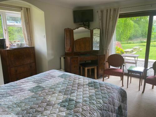 a bedroom with a bed and a desk and a mirror at Lower Thornton Farm in Exeter