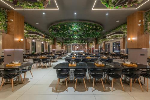 a restaurant with tables and chairs and plants on the ceilings at Hotel Highway Prince Behror in Behror