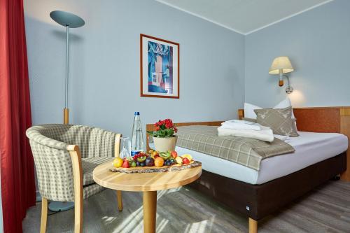 Habitación de hotel con cama y mesa con fruta. en Hotel Königshof en Garmisch-Partenkirchen