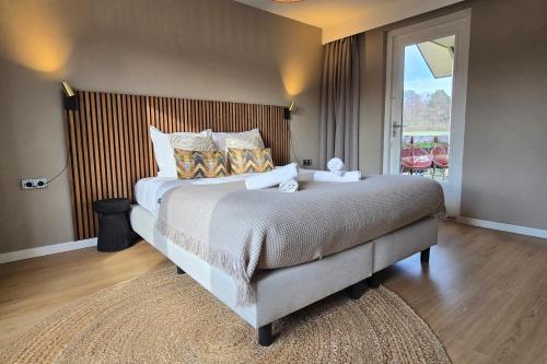 a bedroom with a large bed and a large window at Wellness Villa voor 6 personen incl Sauna & Hottub in Meerssen