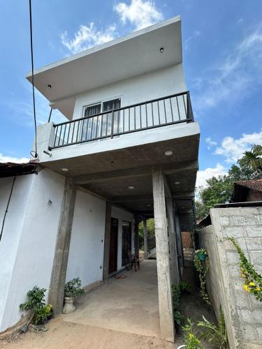 a white house with a balcony on top of it at Andrew Transit Villa - Near Airport in Katunayaka