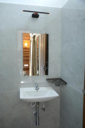 a white bathroom with a sink and a mirror at Hill Woods Yelagiri in Yelagiri