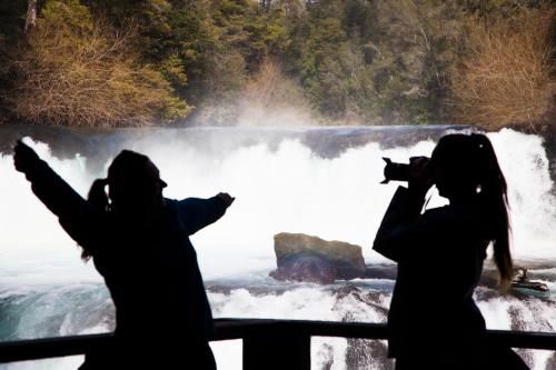 a group of people taking pictures of a waterfall at Huilo Huilo Reino Fungi in Huilo Huilo