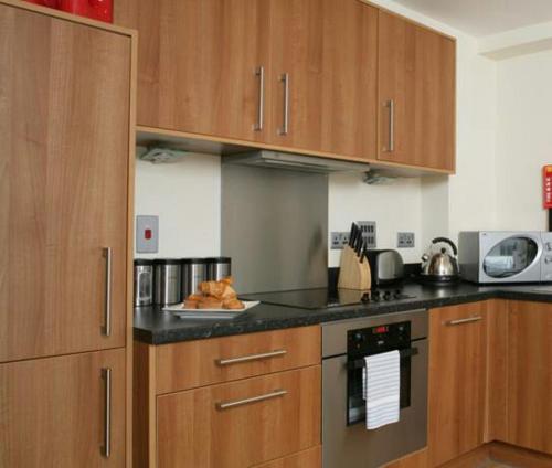 a kitchen with wooden cabinets and a counter top at Leeds City Apartment in Leeds