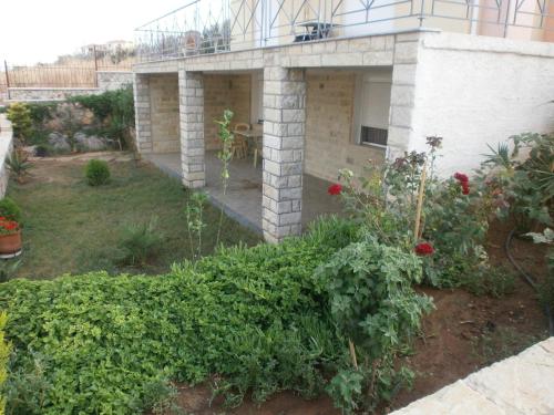 a garden in front of a house with roses at Villa Christine - Maisonettes with fireplace in Aliveri
