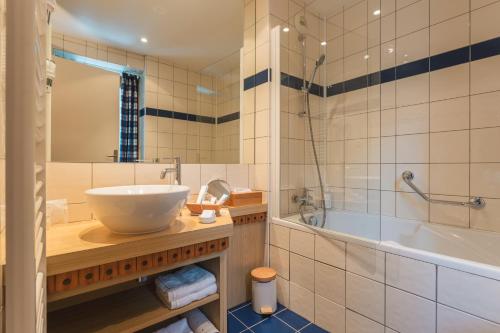 a bathroom with a sink and a bath tub at Hôtel Le Bois Joli in Cauterets