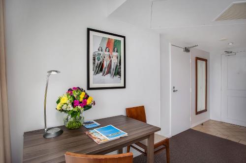 a dining room table with a vase of flowers on it at Mantra Legends Hotel in Gold Coast