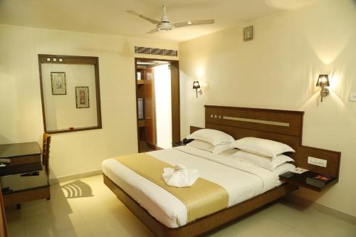 a bedroom with a large bed and a mirror at HOTEL GRAND PLAZzA in Coimbatore