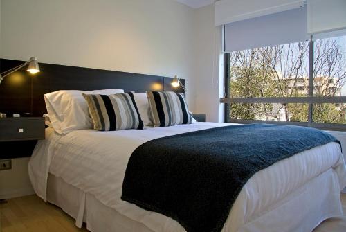 a bedroom with a large bed with a large window at Heidelberg Haus Apart Hotel in Santiago