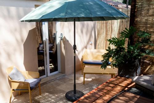 a blue umbrella sitting next to two chairs and a table at Villa Des oliviers in Le Beausset
