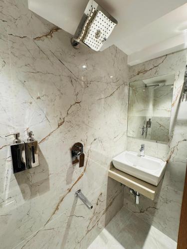 a white bathroom with a sink and a mirror at Hotel Comfort Castle in Mumbai