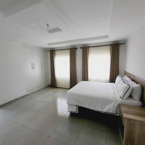 a bedroom with a white bed and two windows at Familyfriendlyhome4u in Bulawayo