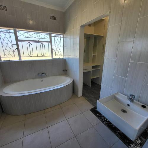 a large bathroom with a tub and a sink at Familyfriendlyhome4u in Bulawayo