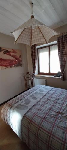 a bedroom with a large bed with an umbrella at Blanche-Roche, gîte en lisière de fôret in Cleurie