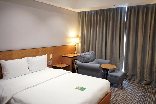 a hotel room with a bed and a desk and chair at Hotel Tour Incheon Airport Hotel & Suites in Incheon