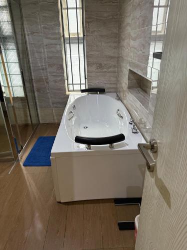 a white tub in a bathroom with a window at Precious Pavilion - Single Rooms in Abuja