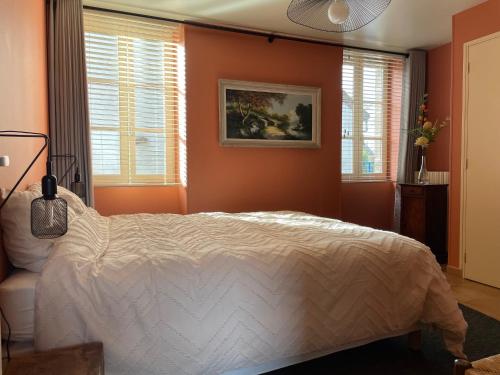 a bedroom with a bed with orange walls and windows at Chez Mémé Delphine in Moutier-Malcard