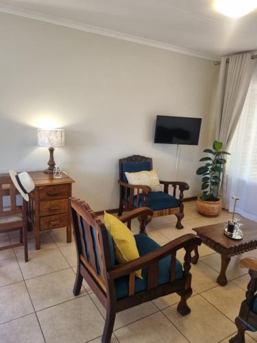 a living room with chairs and a flat screen tv at Bultpark Apartment in Potchefstroom