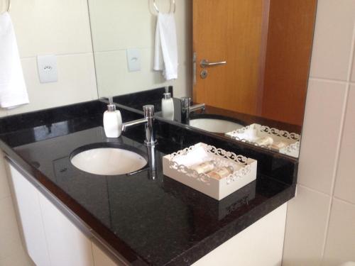 een badkamer met 2 wastafels en een zwart aanrecht bij Apartamento Sol e Mar Maceió in Maceió