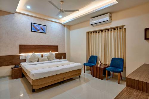 a bedroom with a bed and two blue chairs at Hotel Rajpurush in Kolhapur