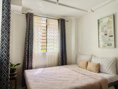 a bedroom with a bed and a window with curtains at Balai Lawaan Cozy Homestay in Iloilo City