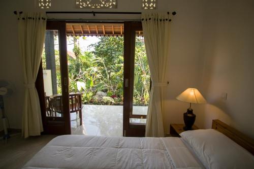 - une chambre avec un lit et une porte coulissante en verre dans l'établissement Pangkung Sari, à Ubud