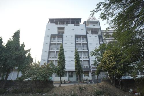 a white building with trees in front of it at Hotel Jay Palace in Kota