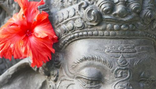 a stone statue with a red flower on it at Kanda Homestay in Sidemen