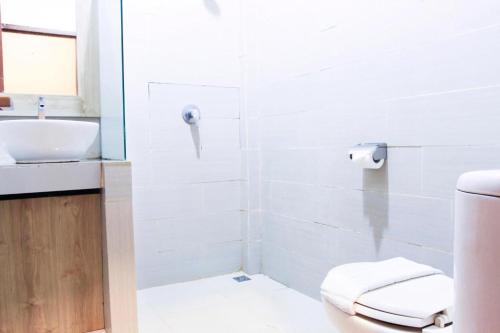 a white bathroom with a toilet and a sink at Bumi Gumati Resort & Convention in Bogor