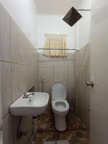 a bathroom with a white toilet and a sink at JCE Comfort & Simplicity in Tacloban