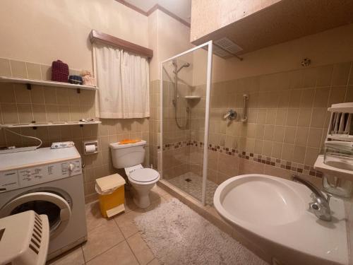 a bathroom with a shower toilet and a washing machine at Sleep to the Sound of Waves - Full Private Apartment in Swakopmund