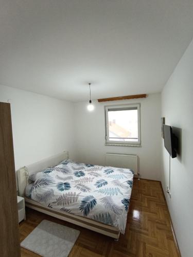 a small bedroom with a bed and a window at Apartman Balkan in Bijeljina