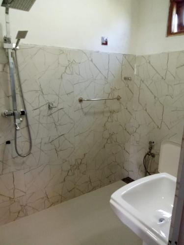 a bathroom with a shower and a white sink at The nest haputale in Haputalegama