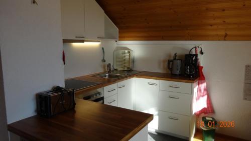 a small kitchen with white cabinets and a wooden counter top at Ferienwohnung Schlemmer in Doren