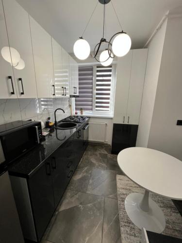 a kitchen with white cabinets and a white table at Ideal House Rent in Petroşani