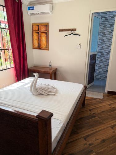 a room with a bed with a swan on it at Mangi Mangi Accomodation in Nungwi