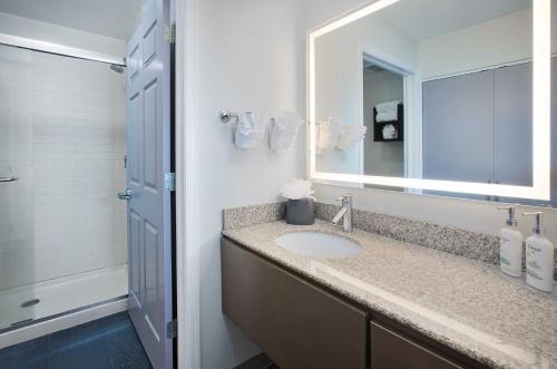 a bathroom with a sink and a mirror and a shower at Staybridge Suites Lincoln North East by IHG in Lincoln