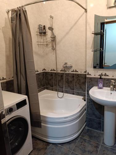 a bathroom with a tub and a sink and a washing machine at Vintage Veranda Apartment in Itʼkhvisi