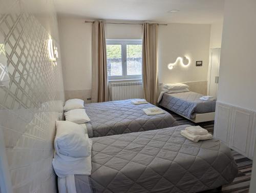 a hotel room with two beds and a window at Bed and Breakfast Mezzanotte in Balvano