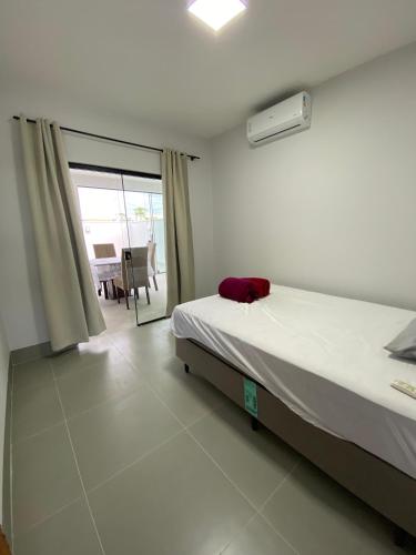 a bedroom with a bed and a balcony with a table at Casa com piscina praia do ervino in São Francisco do Sul