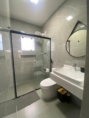 a bathroom with a shower and a toilet and a sink at Casa com piscina praia do ervino in São Francisco do Sul