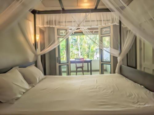 a bedroom with a bed and a window with a table at White Villa - Homestay in Tangalle