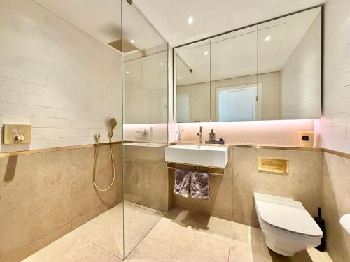 a bathroom with a toilet and a sink and a mirror at Battersea Power Apartments in London