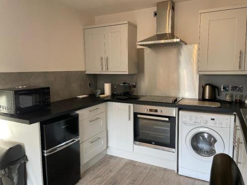a kitchen with white cabinets and a washer and dryer at The Mews in the heart of Stockton Heath in Warrington