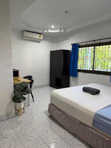 a bedroom with a bed and a desk and a window at Secret Lanta Guesthouse in Ko Lanta