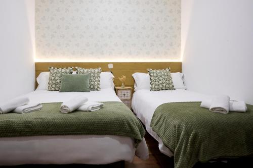 a bedroom with two beds with green and white sheets at Apartamentos Fuencarral II in Madrid