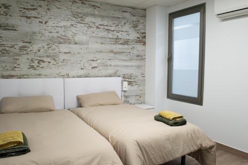 two beds in a room with a brick wall at Suites TDJ Centro in Torredonjimeno
